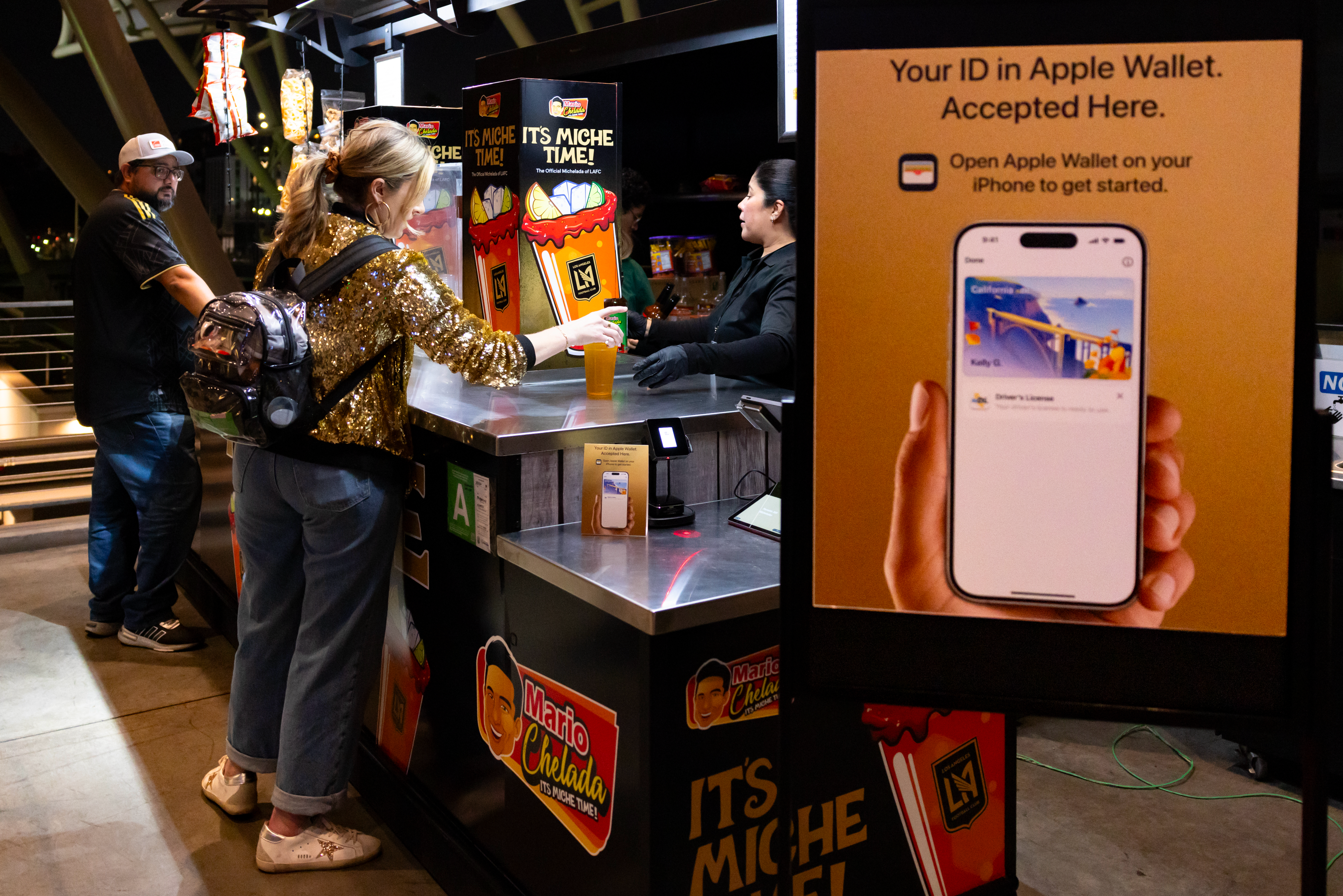 Fan at BMO Stadium concession stand with Apple Wallet ID verification signage