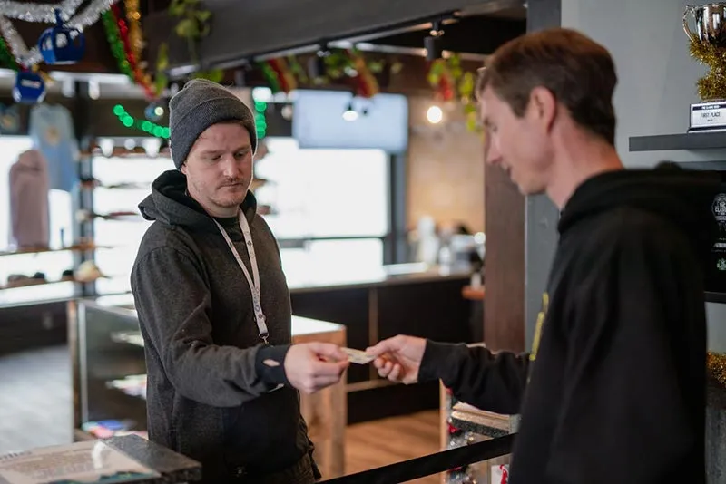 Dispensary budtender checking a customer's driver's license at the counter